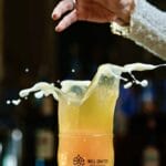 A pint glass of Well Crafted Beer splashing